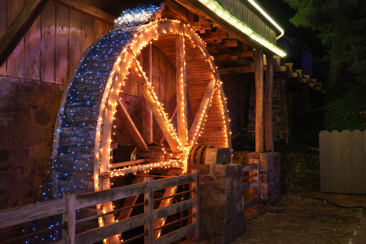 Ein Wasserrad, das nachts mit Weihnachtslichtern erstrahlt.